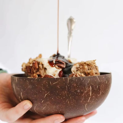 Natural coconut shell bowl used for serving breakfast with granola and syrup